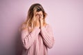 Young beautiful blonde woman wearing casual pink sweater over isolated background with sad expression covering face with hands Royalty Free Stock Photo