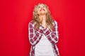 Young beautiful blonde woman wearing casual shirt standing over isolated red background begging and praying with hands together Royalty Free Stock Photo