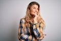 Young beautiful blonde woman wearing casual shirt standing over isolated white background with hand on chin thinking about Royalty Free Stock Photo