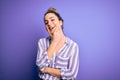 Young beautiful blonde woman wearing casual striped shirt standing over purple background looking confident at the camera smiling Royalty Free Stock Photo