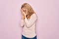 Young beautiful blonde woman wearing casual sweater and glasses over pink background with sad expression covering face with hands Royalty Free Stock Photo