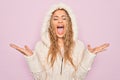 Young beautiful blonde woman wearing casual sweater with hood over isolated pink background celebrating mad and crazy for success