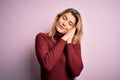 Young beautiful blonde woman wearing casual sweater over isolated pink background sleeping tired dreaming and posing with hands Royalty Free Stock Photo