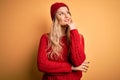 Young beautiful blonde woman wearing casual sweater and wool cap over white background with hand on chin thinking about question, Royalty Free Stock Photo