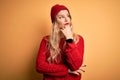 Young beautiful blonde woman wearing casual sweater and wool cap over white background with hand on chin thinking about question, Royalty Free Stock Photo