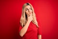 Young beautiful blonde woman wearing casual t-shirt standing over isolated red background Thinking worried about a question, Royalty Free Stock Photo