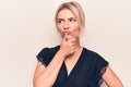 Young beautiful blonde woman wearing casual t-shirt standing over isolated white background with hand on chin thinking about Royalty Free Stock Photo