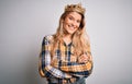 Young beautiful blonde woman wearing golden crown of queen over isolated white background happy face smiling with crossed arms Royalty Free Stock Photo