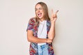 Young beautiful blonde woman wearing modern clothes smiling with happy face winking at the camera doing victory sign Royalty Free Stock Photo