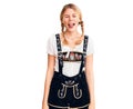 Young beautiful blonde woman wearing oktoberfest dress sticking tongue out happy with funny expression Royalty Free Stock Photo