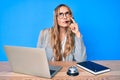 Young beautiful blonde woman wearing operator headset at the call center office serious face thinking about question with hand on Royalty Free Stock Photo