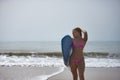 Young, beautiful, blonde woman, wearing a pink bikini, posing with a blue surfboard under her arm, in sensual and provocative Royalty Free Stock Photo