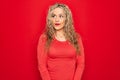 Young beautiful blonde woman wearing red casual t-shirt standing over isolated background smiling looking to the side and staring Royalty Free Stock Photo