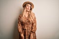 Young beautiful blonde woman wearing summer dress and hat over isolated white background smiling looking to the side and staring Royalty Free Stock Photo