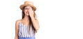 Young beautiful blonde woman wearing summer hat covering one eye with hand, confident smile on face and surprise emotion Royalty Free Stock Photo