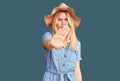 Young beautiful blonde woman wearing summer hat and dress doing stop sing with palm of the hand Royalty Free Stock Photo