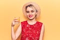 Young beautiful blonde woman wearing summer hat drinking glass of orange juice looking positive and happy standing and smiling Royalty Free Stock Photo