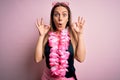 Young beautiful blonde woman wearing swimsuit and floral Hawaiian lei over pink background looking surprised and shocked doing ok Royalty Free Stock Photo