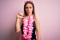 Young beautiful blonde woman wearing swimsuit and floral Hawaiian lei over pink background looking unhappy and angry showing Royalty Free Stock Photo