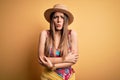 Young beautiful blonde woman wearing swimsuit and summer hat over yellow background shaking and freezing for winter cold with sad Royalty Free Stock Photo