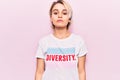 Young beautiful blonde woman wearing t shirt with diversity word message with serious expression on face