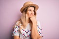 Young beautiful blonde woman wearing t-shirt and hat over isolated pink background with hand on chin thinking about question, Royalty Free Stock Photo