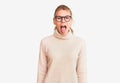 Young beautiful blonde woman wearing turtleneck sweater and glasses sticking tongue out happy with funny expression Royalty Free Stock Photo