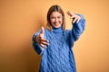 Young beautiful blonde woman wearing turtleneck sweater over yellow isolated background looking at the camera smiling with open Royalty Free Stock Photo