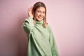 Young beautiful blonde woman wearing winter wool sweater over pink isolated background smiling with hand over ear listening an Royalty Free Stock Photo