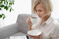 Young beautiful blonde woman in white shirt and glasses is sitting on the sofa in bright office against the window Royalty Free Stock Photo