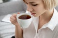 Young beautiful blonde woman in white shirt and glasses is sitting on the sofa in bright office against the window Royalty Free Stock Photo