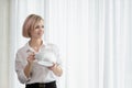 Young beautiful blonde woman in white shirt and glasses is sitting on the sofa in bright office against the window Royalty Free Stock Photo