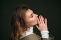 A young beautiful blonde woman in a white turtleneck and a man`s jacket poses on a green olive background in the studio. Royalty Free Stock Photo