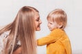 Young beautiful blonde woman looks at her daughter Todler on a white background