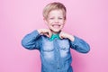 Young beautiful boy with blue shirt and butterfly tie. Studio portrait over pink background. Royalty Free Stock Photo