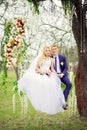 Young and beautiful bride and groom sitting on a white swing in Royalty Free Stock Photo