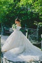Young beautiful bride in luxury dress with a long train posing in country hotel