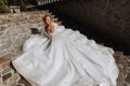 young beautiful bride in off-shoulder wedding dress lying on stone steps, fashion shot under harsh sunlight Royalty Free Stock Photo