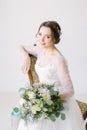 Young beautiful bride sitting in a chair and smiling, close-up. Beauty portrait of bride wearing fashion wedding dress Royalty Free Stock Photo