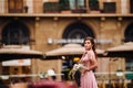 A young beautiful bride stands at the center of the Old city of Florence in Italy. Bride in a beautiful pink dress with a bouquet