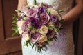 Young beautiful bride in white dress holding wedding bouquet, bouquet of bride from rose cream spray, rose bush, rose purple Memor