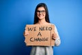 Young beautiful brunette activist woman holding banner protesting to change with a happy face standing and smiling with a