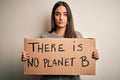 Young beautiful brunette activist woman protesting for save the planet holding banner with a confident expression on smart face