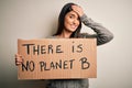 Young beautiful brunette activist woman protesting for save the planet holding banner stressed with hand on head, shocked with