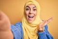 Young beautiful brunette arab woman wearing islamic hijab make selfie by camera very happy and excited, winner expression Royalty Free Stock Photo