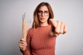 Young beautiful brunette artist woman holding painter brushes over white background pointing with finger to the camera and to you, Royalty Free Stock Photo