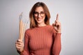 Young beautiful brunette artist woman holding painter brushes over white background surprised with an idea or question pointing Royalty Free Stock Photo