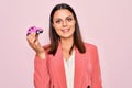 Young beautiful brunette business woman holding small car toy over pink background looking positive and happy standing and smiling Royalty Free Stock Photo