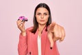 Young beautiful brunette business woman holding small car toy over pink background pointing with finger to the camera and to you, Royalty Free Stock Photo