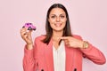 Young beautiful brunette business woman holding small car toy over pink background Smiling happy pointing with hand and finger Royalty Free Stock Photo